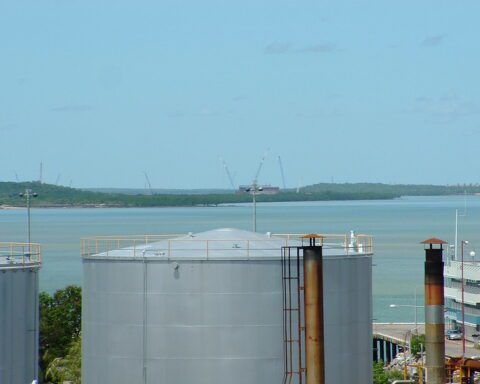 Aerial view of the Darwin LNG gas plant at Wickham Point under construction in 2004, with fuel tanks in the foreground and cranes against the skyline.