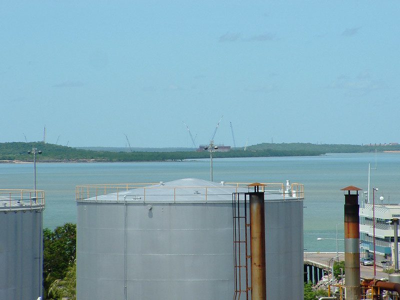 Aerial view of the Darwin LNG gas plant at Wickham Point under construction in 2004, with fuel tanks in the foreground and cranes against the skyline.