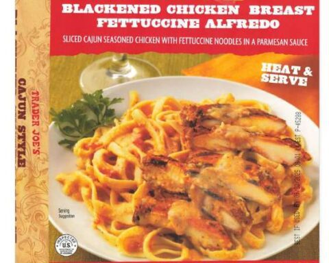 Trader Joe's Cajun Style Blackened Chicken Breast Fettuccine Alfredo in red packaging, showing the prepared dish with sliced blackened chicken and fettuccine pasta in creamy sauce.