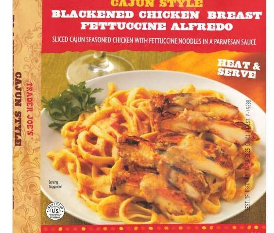 Trader Joe's Cajun Style Blackened Chicken Breast Fettuccine Alfredo in red packaging, showing the prepared dish with sliced blackened chicken and fettuccine pasta in creamy sauce.