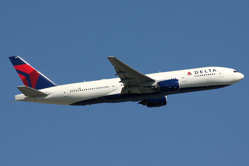 Delta Air Lines Boeing 777-200 aircraft with registration N862DA flying against a blue sky, showing the distinctive red and blue Delta livery with white fuselage.