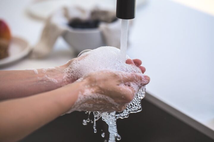 Representative Image. Person washing hands with soap and water at a sink, creating a thick lather of bubbles between their palms.