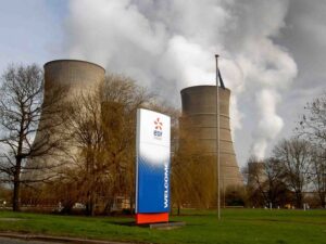 Cooling towers at an EDF power station with trees in the foreground against a blue sky background.