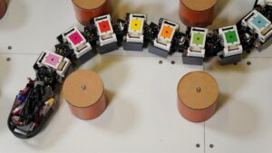Agnathax eel-inspired robot with colorful segmented body maneuvering through cylindrical pegs on a testing surface