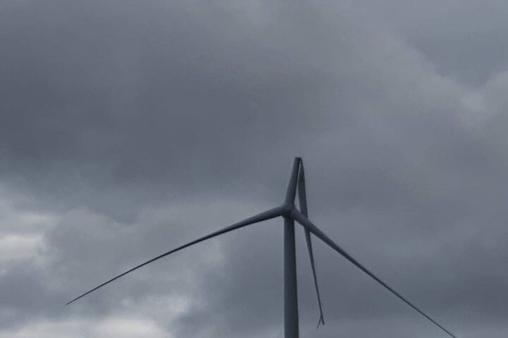 Broken wind turbine blade at Flyers Creek Wind Farm in NSW against a grey cloudy sky.