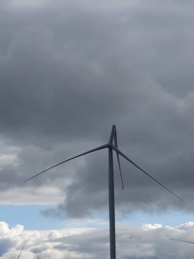 Broken wind turbine blade at Flyers Creek Wind Farm in NSW against a grey cloudy sky.
