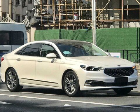 White 2019 Ford Taurus sedan parked on a street with construction scaffolding visible in the background.