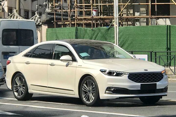 White 2019 Ford Taurus sedan parked on a street with construction scaffolding visible in the background.