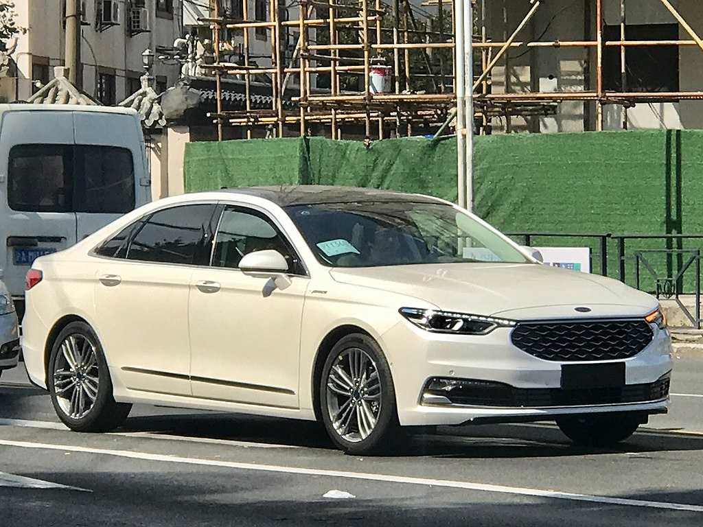 White 2019 Ford Taurus sedan parked on a street with construction scaffolding visible in the background.