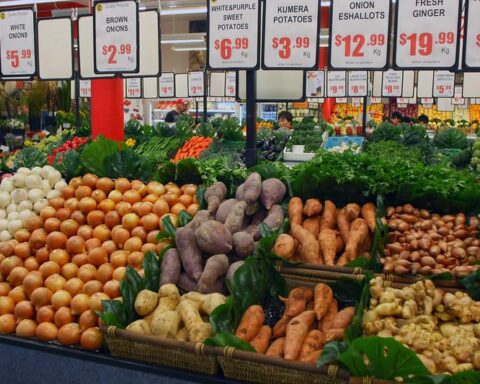 Fresh produce display at Sydney Fish Market featuring onions, potatoes, ginger, and garlic with price signs in Australian dollars.