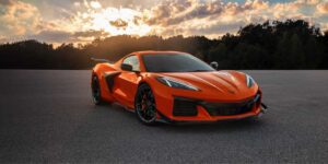 Orange 2025 Chevrolet Corvette Z06 supercar parked on asphalt at sunset with dramatic sky in background