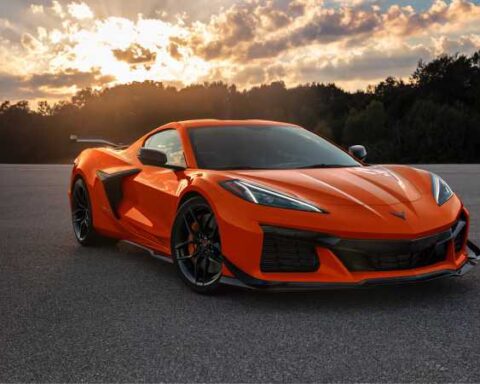 Orange 2025 Chevrolet Corvette Z06 supercar parked on asphalt at sunset with dramatic sky in background