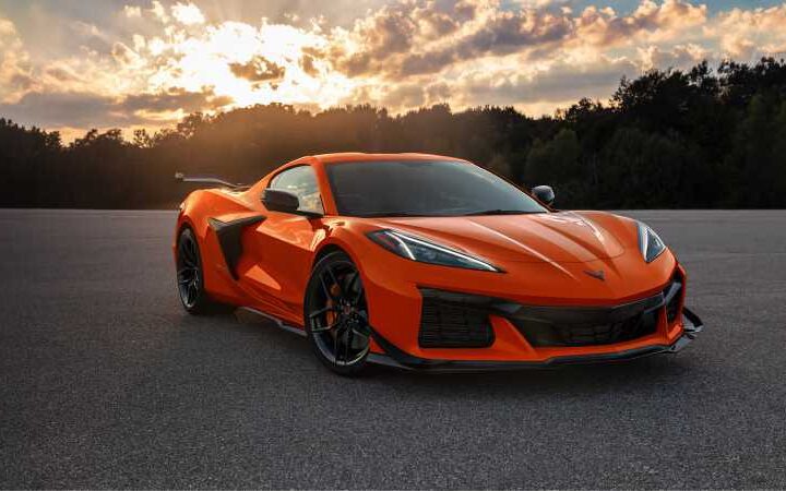 Orange 2025 Chevrolet Corvette Z06 supercar parked on asphalt at sunset with dramatic sky in background
