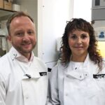 Professor Ed Wild and Professor Sarah Tabrizi from UCL's Huntington's Disease Centre standing together in a laboratory wearing white lab coats with UCL insignia.