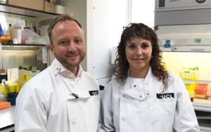 Professor Ed Wild and Professor Sarah Tabrizi from UCL's Huntington's Disease Centre standing together in a laboratory wearing white lab coats with UCL insignia.
