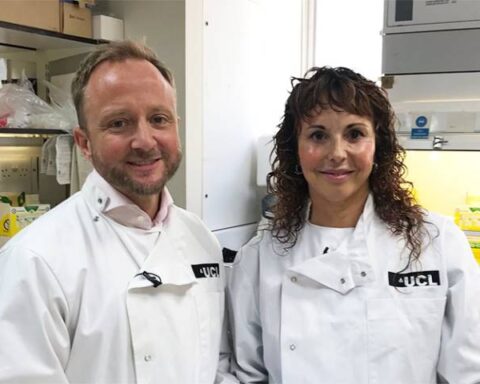 Professor Ed Wild and Professor Sarah Tabrizi from UCL's Huntington's Disease Centre standing together in a laboratory wearing white lab coats with UCL insignia.