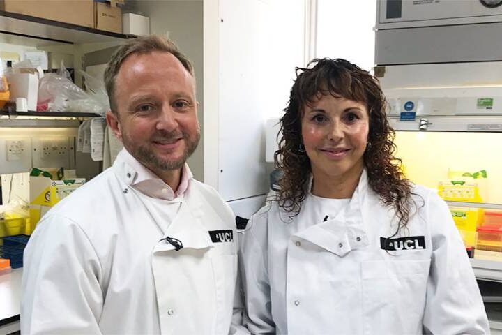 Professor Ed Wild and Professor Sarah Tabrizi from UCL's Huntington's Disease Centre standing together in a laboratory wearing white lab coats with UCL insignia.