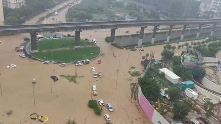 Flooded Gurgaon underpass with cars stranded in brown rainwater after heavy monsoon rainfall, highlighting poor drainage and urban flooding issues.
