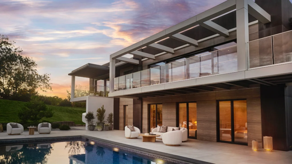 Drone view of the Omaze Surrey Hills house showing modern architecture with flat roof, large windows, and integration with surrounding woodland and gardens.