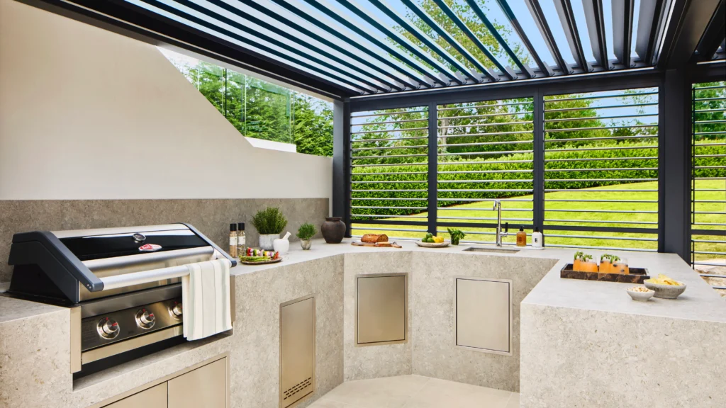 Outdoor kitchen area of the Omaze Surrey Hills prize house featuring stone countertops, built-in grill, and covered dining space.