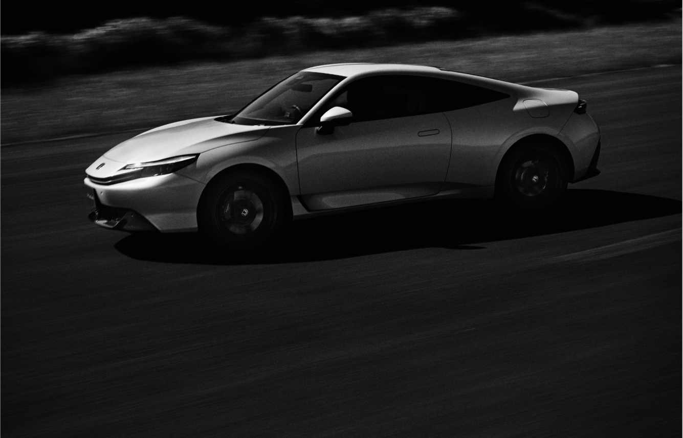 White 2026 Honda Prelude hybrid sports coupe with sleek fastback design, flush door handles and blue accent details on the front bumper