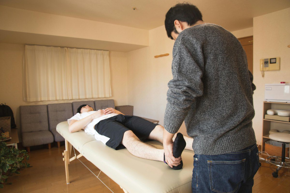 Physiotherapist holding a patient’s foot during a therapy session in a clinical setting, highlighting professional care amid India’s ongoing debate over the “Dr.” title.
