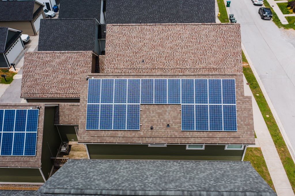 Aerial view of solar panels installed on the roof of a suburban house with neighboring homes visible