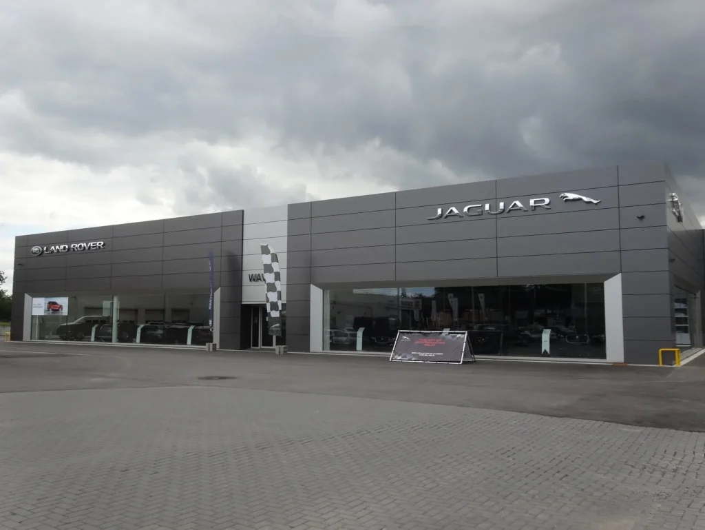 Exterior view of a Jaguar Land Rover dealership in Wavre, Belgium, with modern grey façade and showroom windows.
