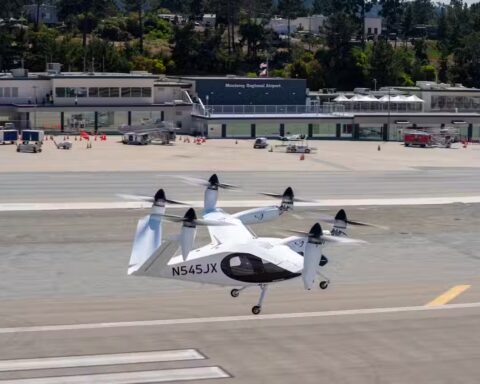 A white Joby Aviation electric vertical takeoff and landing (eVTOL) aircraft with six tilting propellers on the runway at Monterey Regional Airport.
