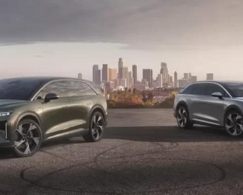 Two Lucid Gravity electric SUVs with aerodynamic designs parked on a hill overlooking Los Angeles skyline at sunset