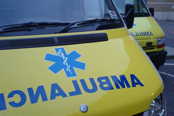 Close-up view of yellow London ambulance vehicle with blue NHS star of life medical symbol visible on the side.