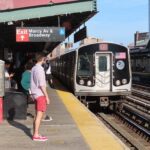 NYC subway train arriving at Marcy Avenue station in Williamsburg with passengers waiting on the platform