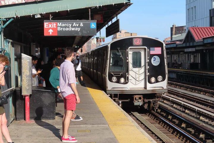 NYC subway train arriving at Marcy Avenue station in Williamsburg with passengers waiting on the platform