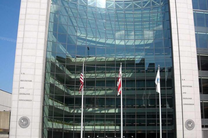 U.S. Securities and Exchange Commission headquarters building in Washington D.C., featuring a modern glass facade with American flags displayed at the entrance.