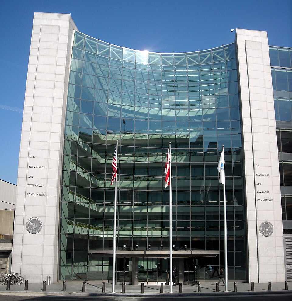U.S. Securities and Exchange Commission headquarters building in Washington D.C., featuring a modern glass facade with American flags displayed at the entrance.