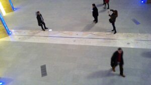 Security camera footage showing several people walking through an indoor corridor, likely seeking relief from extreme outdoor temperatures.