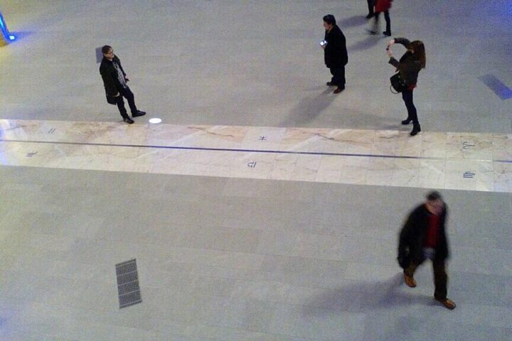 Security camera footage showing several people walking through an indoor corridor, likely seeking relief from extreme outdoor temperatures.