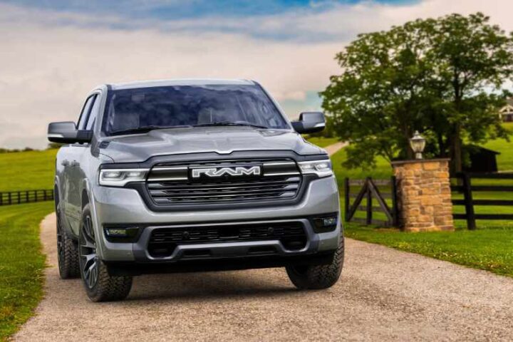 2026 Ram 1500 REV pickup truck in silver, shown driving on a highway with desert landscape in the background.