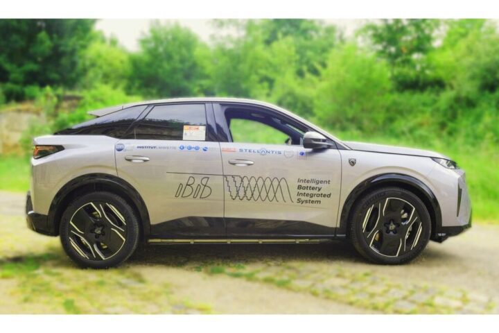 A white Peugeot e-3008 SUV with "Intelligent Battery Integrated System" graphics on the side, parked on a path with green foliage background.