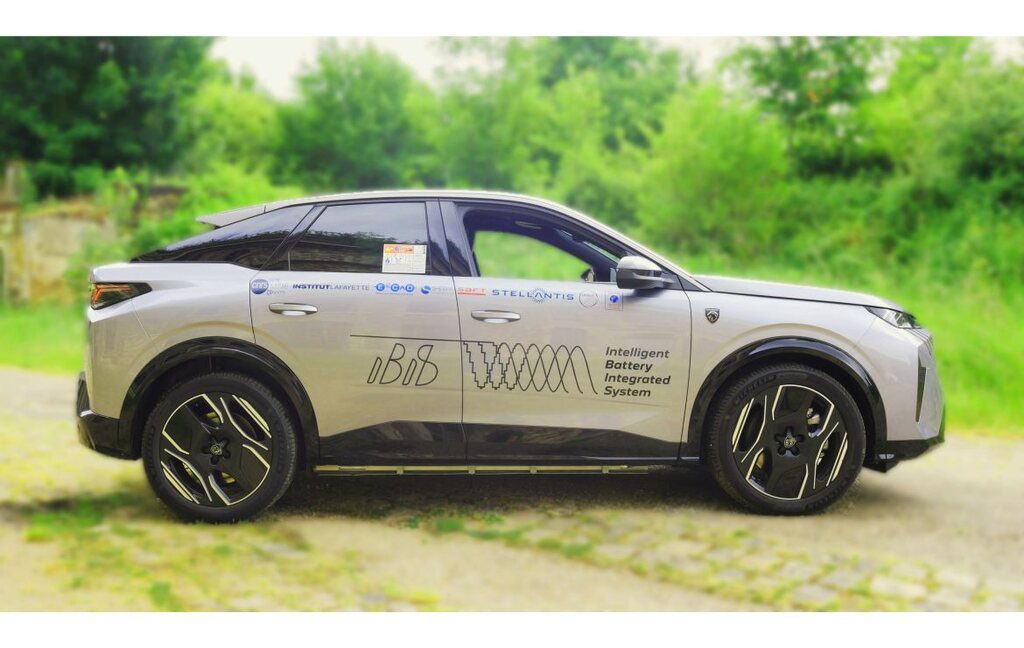 A white Peugeot e-3008 SUV with "Intelligent Battery Integrated System" graphics on the side, parked on a path with green foliage background.