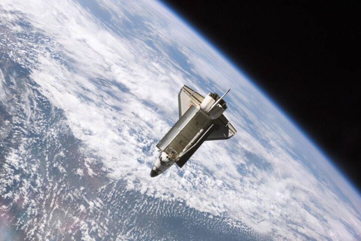 Space shuttle orbiting Earth against the backdrop of clouds and atmosphere, demonstrating the harsh environment where stem cells experience accelerated aging