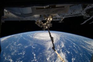 Aerial view of Super Typhoon Ragasa from the International Space Station showing the massive storm system's eye and spiral cloud formations over the ocean, with part of the ISS structure visible in the foreground.