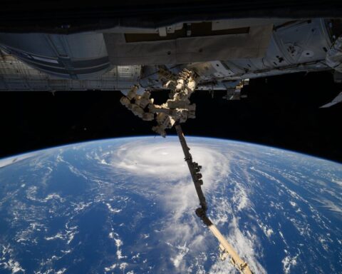 Aerial view of Super Typhoon Ragasa from the International Space Station showing the massive storm system's eye and spiral cloud formations over the ocean, with part of the ISS structure visible in the foreground.