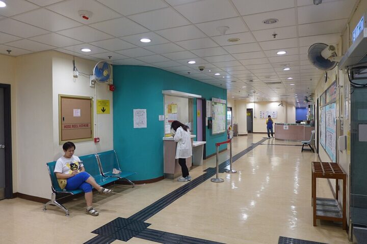 Representative Image. Interior lobby of Sai Wan Ho Sports Centre showing a reception desk with staff, waiting area with blue walls, and a person sitting on chairs in the waiting area.