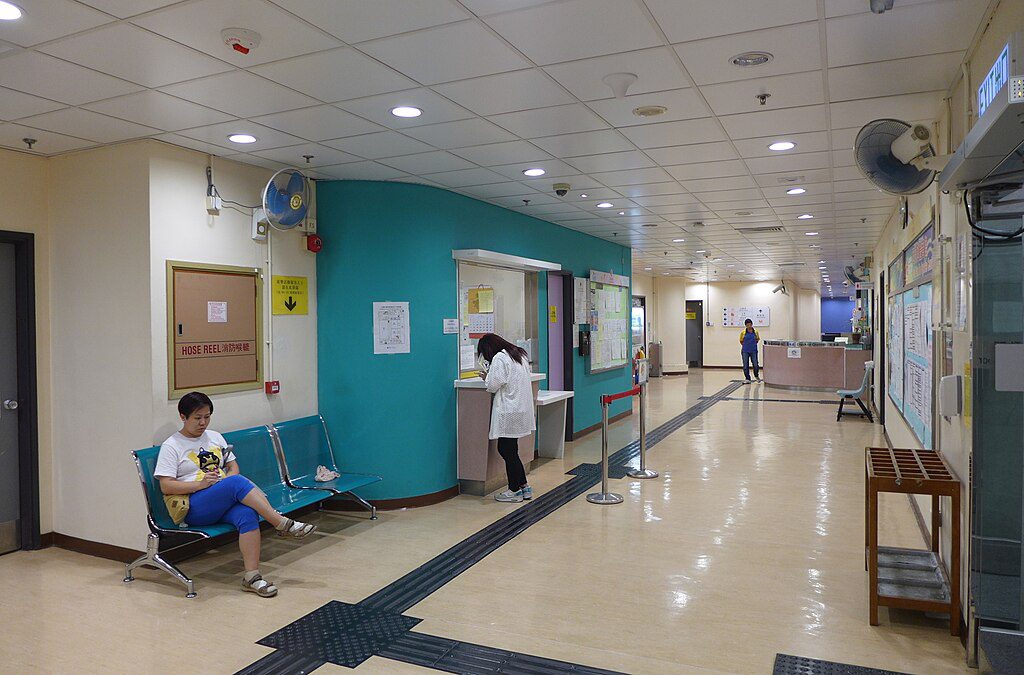 Representative Image. Interior lobby of Sai Wan Ho Sports Centre showing a reception desk with staff, waiting area with blue walls, and a person sitting on chairs in the waiting area.