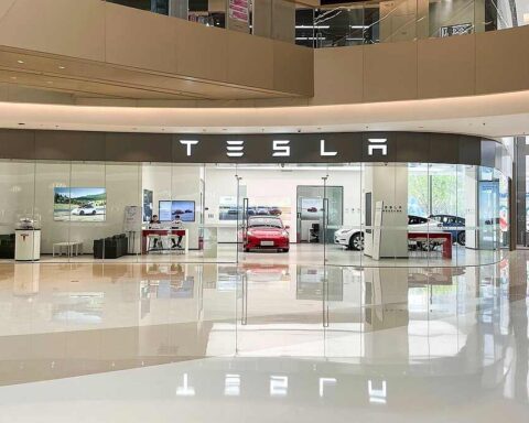 Tesla showroom with glass storefront displaying Tesla logo and vehicles on display at Grand Plaza in Zhengzhou Hi-Tech Zone, China.