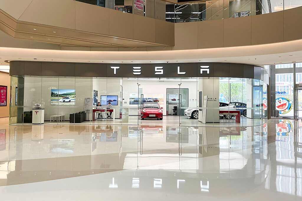 Tesla showroom with glass storefront displaying Tesla logo and vehicles on display at Grand Plaza in Zhengzhou Hi-Tech Zone, China.
