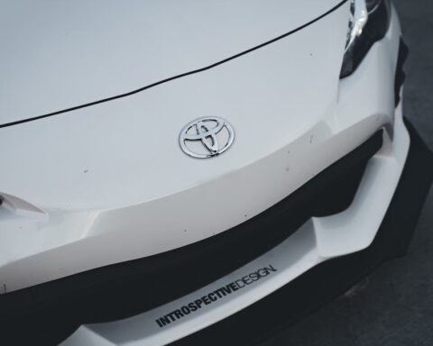 Close-up of a white Toyota vehicle showing the Toyota logo on the front bumper with "INTROSPECTIVEDESIGN" text visible on the lower portion