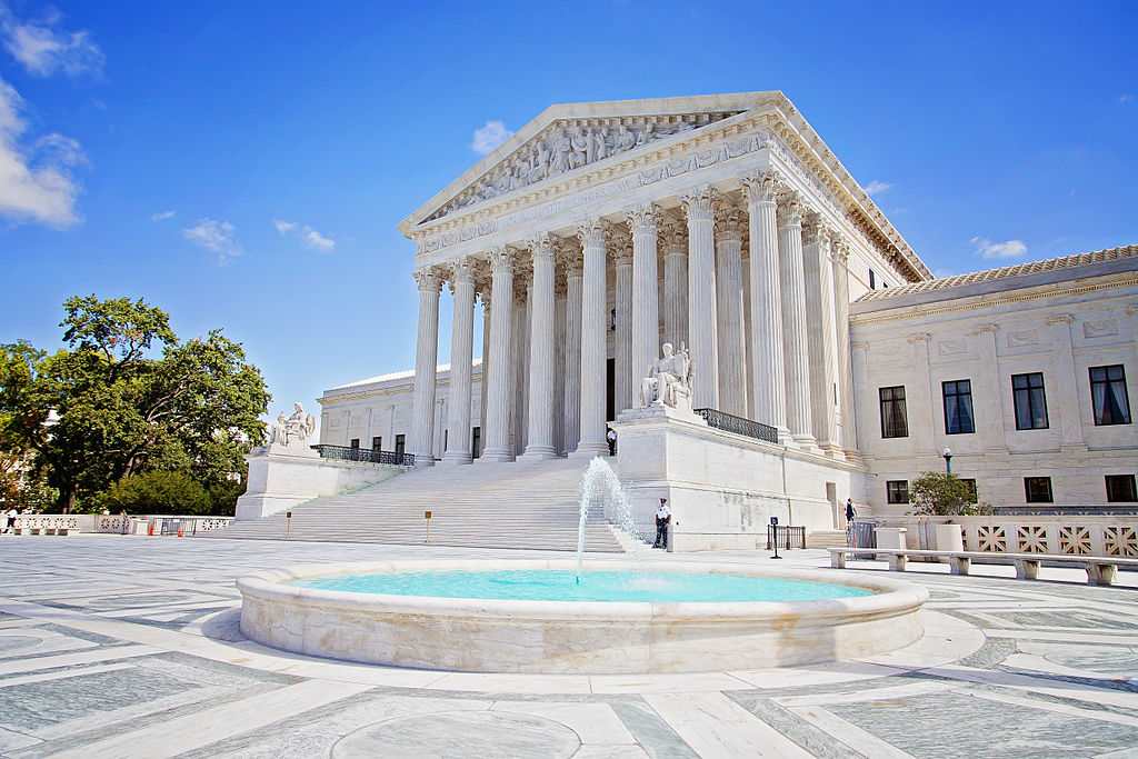 United States Supreme Court Building with white marble columns and steps leading to the entrance on a clear day