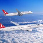 A Boeing 787 Dreamliner in Turkish Airlines livery flying above clouds, showcasing the aircraft's distinctive swept wings and advanced aerodynamic design.